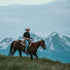 Man wearing The Bandera shirt riding horse outdoors with mountain backdrop