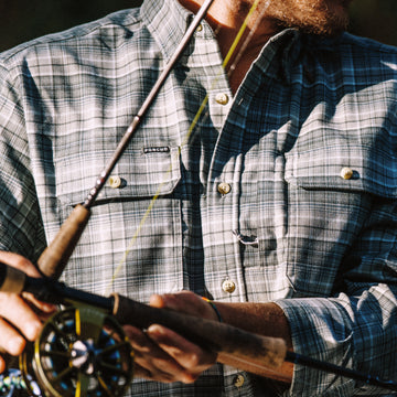 Close-up of a man wearing The Cashiers plaid shirt holding a fishing rod outdoors
