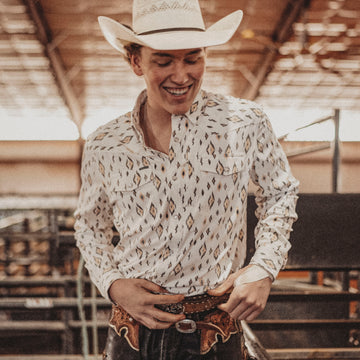 Young man wearing The Rattler outdoor shirt and cowboy hat in rustic barn setting