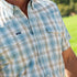 Close-up of a man wearing The Sandbar shirt with a green and white plaid pattern outdoors on a sunny day