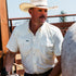 Man wearing The Medicine Bow shirt and cowboy hat outdoors by a fence