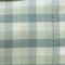 Close-up of light green and white plaid fabric with stitching detail
