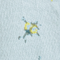 Close-up of light blue fabric with a small yellow and black ink stain or print detail
