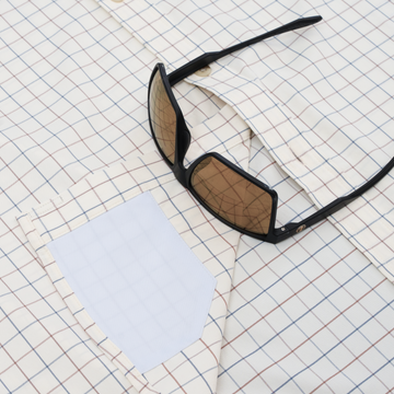 Close up of sunglasses on hidden cleaner fabric on blue and red button down
