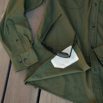 close up of lens cloth on bottom of moss green flannel shirt