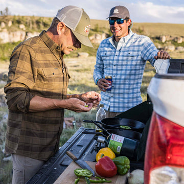 two guys grilling on back of truck tailgate